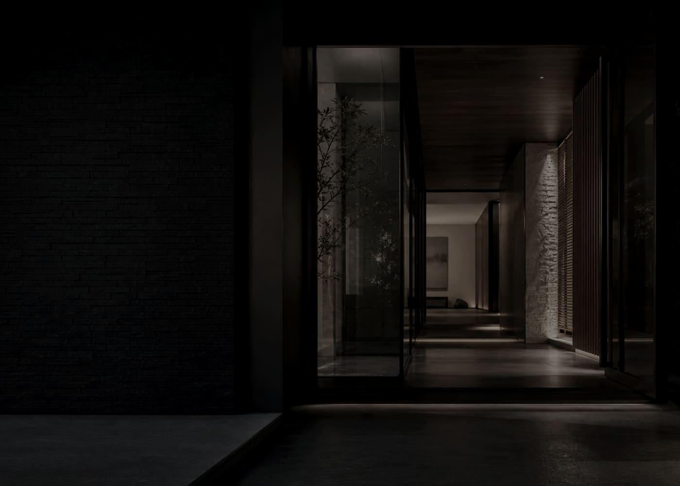 A quiet architectural entry threshold with stone, glass, and warm light